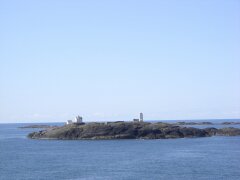 Schäre mit Leuchtturm vor Bergen