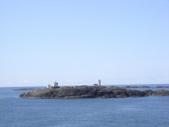 Schäre mit Leuchtturm vor Bergen